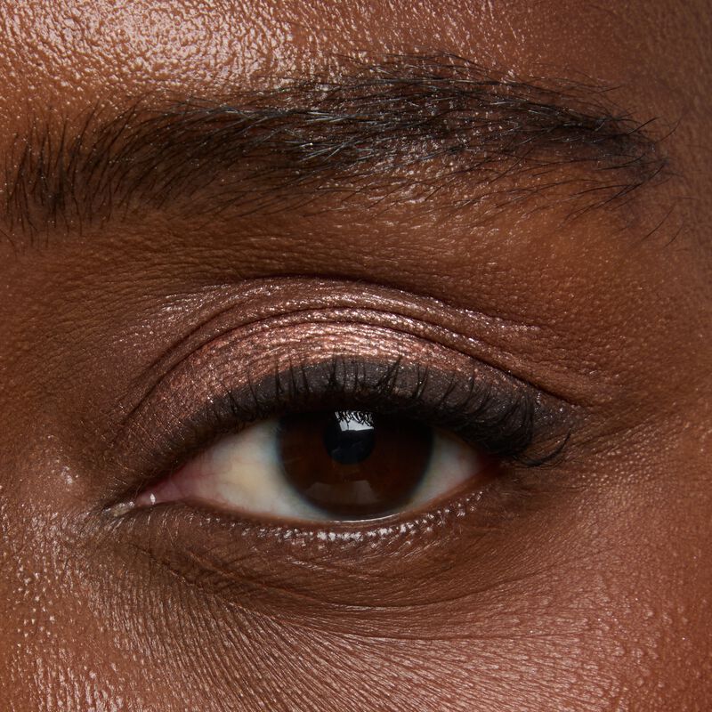 Deep skinned model wearing Mary kay Eye Shadow Sticks in shades Copper Nova and Black Obsidian
